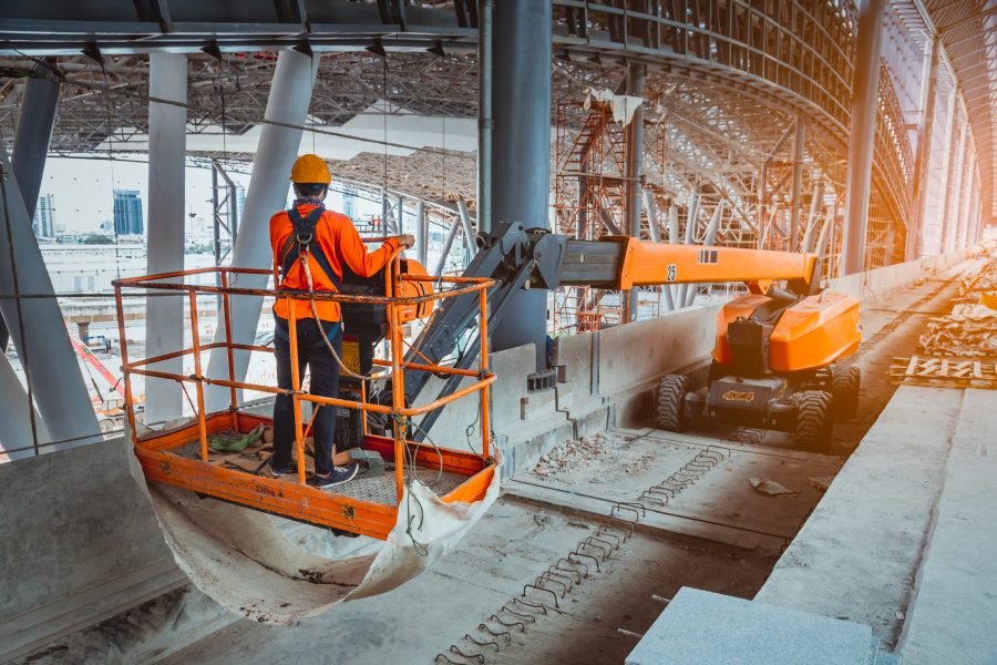 A Engineer wearing safety uniform and safety helmet ,controlling straight Boom Lift to construction roof on sky rail train platform station .